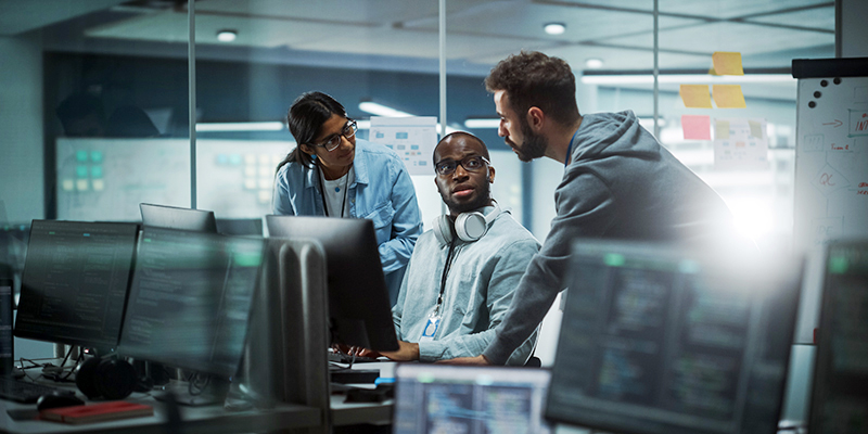 Diverse Group of Professionals Meeting in Modern Office: Brainstorming IT Programmers Use Computer Together, Talk Strategy, Discuss Planning. Software Engineers Develop Inspirational App Program