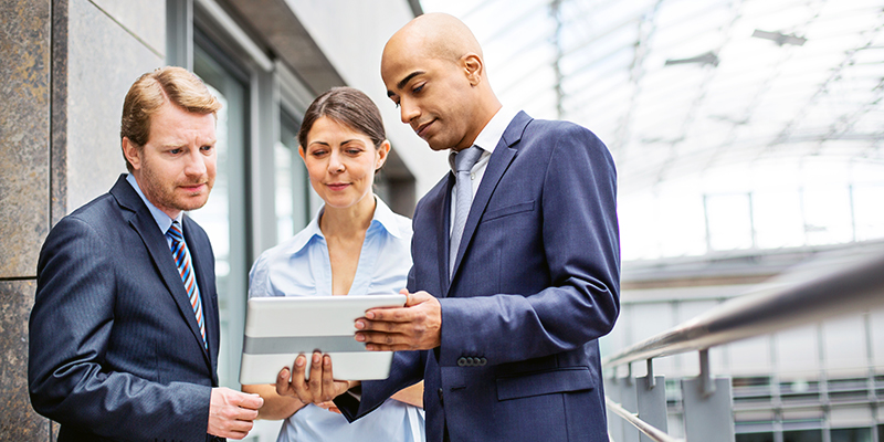 Three colleagues discussing work using a tablet computer in office