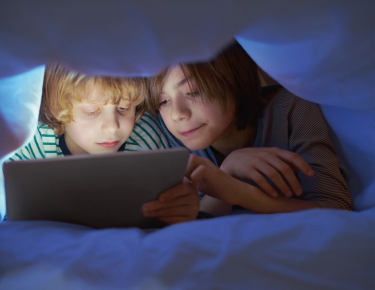 Kids under blanket with tablet