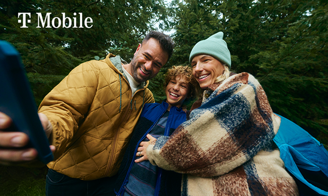 A smiling family of three outdoors taking a selfie.